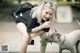 A woman kneeling down next to a dog on a sidewalk.