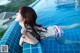 A woman in a bikini laying on the edge of a swimming pool.