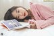 A woman laying on a bed reading a book.