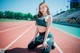 A woman sitting on a running track with her legs crossed.