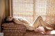 A woman laying on top of a bed next to a window.