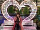 A woman sitting on a bench in front of a heart shaped sign.