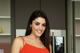 A woman in a red dress standing in front of a refrigerator.