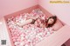 A woman laying in a bathtub filled with pink and white balloons.