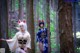 A couple of women in kimonos standing in the woods.