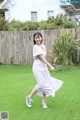 A woman in a gray dress is running in the grass.