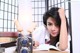 A woman sitting at a desk with a camera and books.