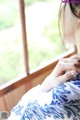 A woman in a blue and white kimono looking out a window.