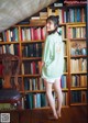 A woman standing in front of a bookshelf full of books.